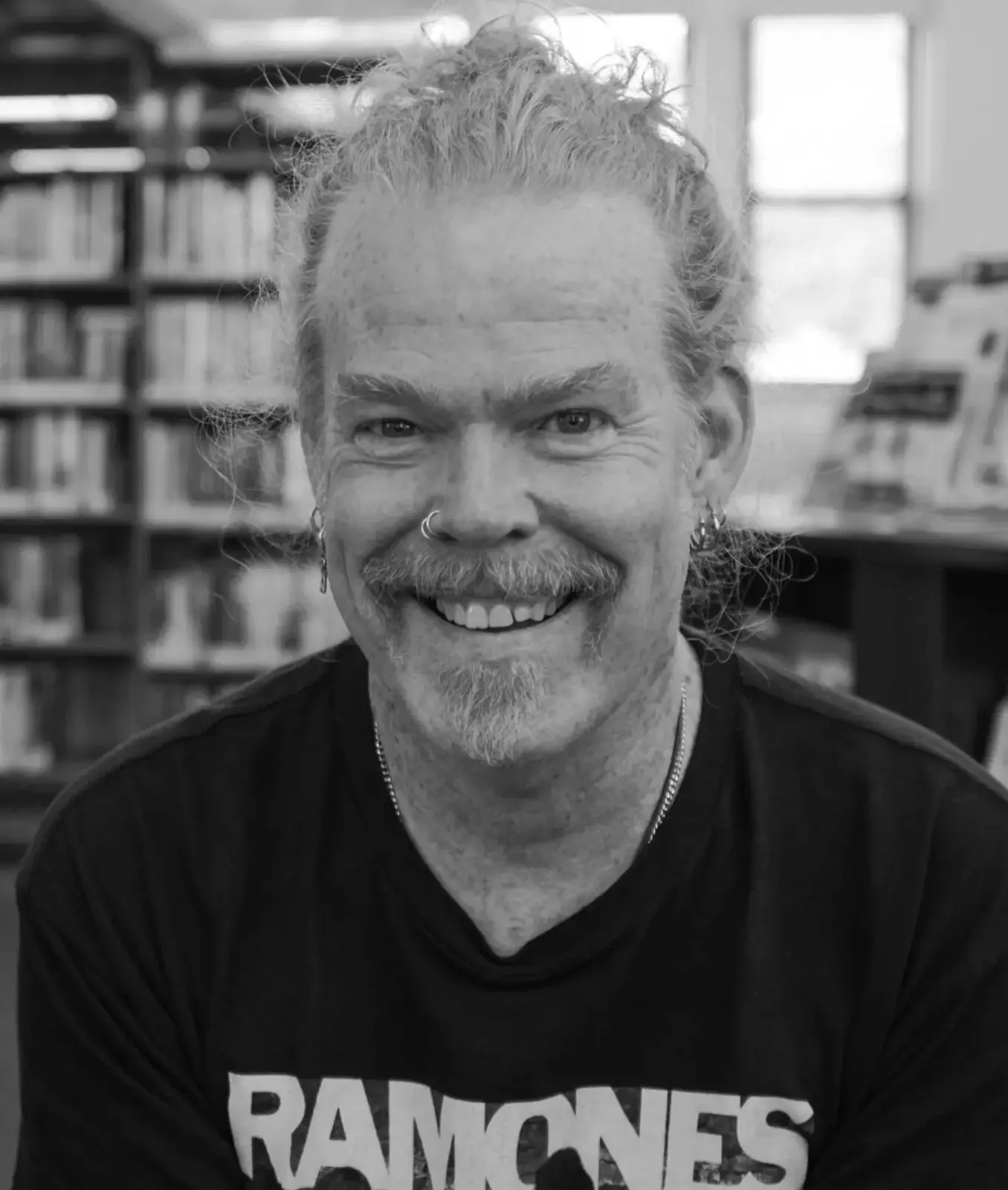 Smiling man with gray hair and beard in a black shirt.