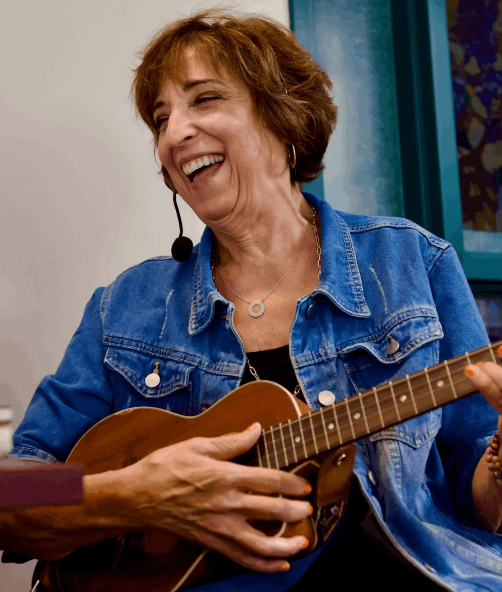 A joyful woman playing a ukulele and smiling.