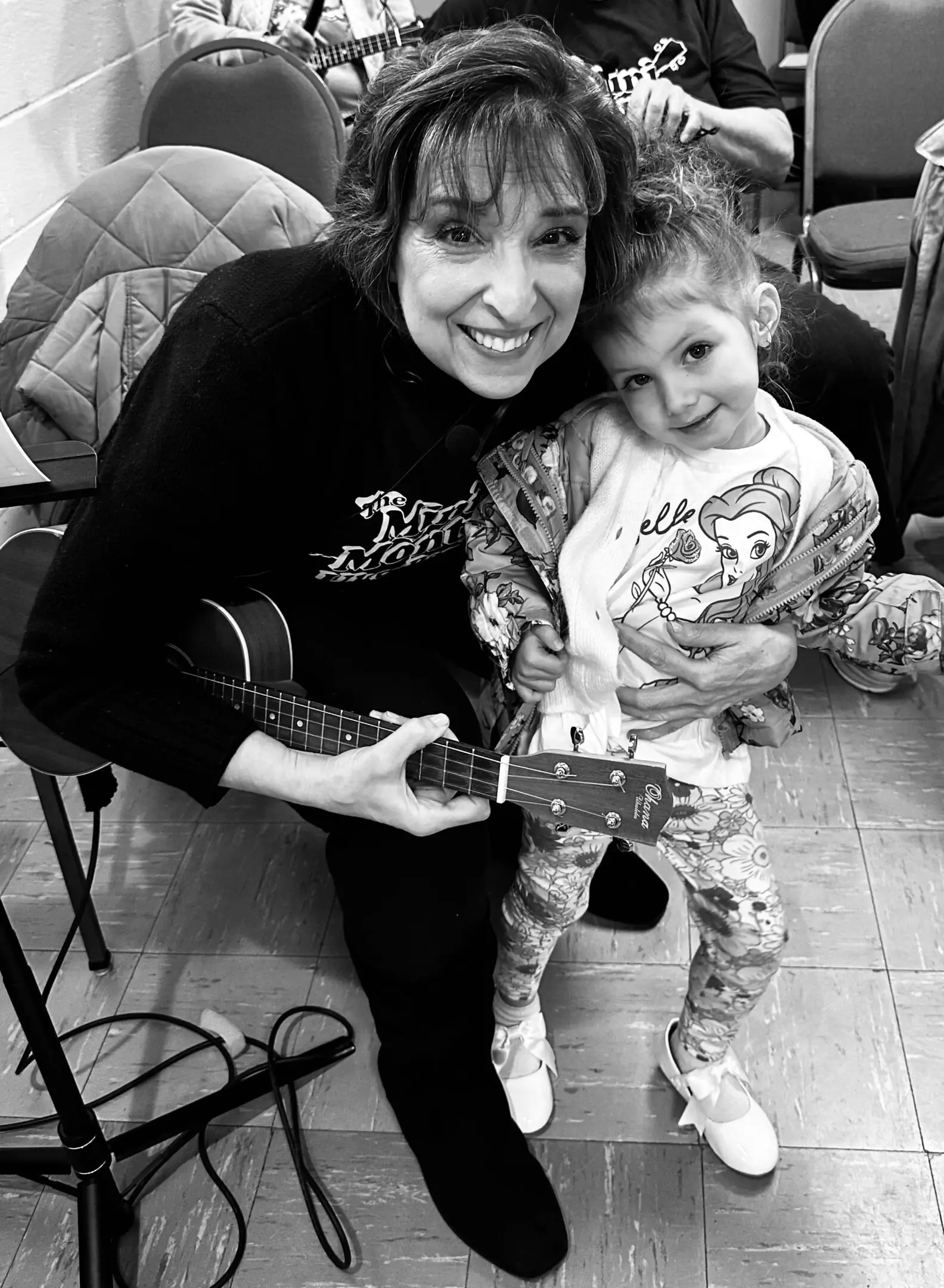 A joyful woman and child share a moment holding a toy guitar.